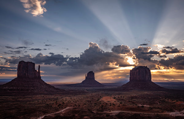 Sunrise over Monument Valley with distinctive rock formations and dramatic clouds.