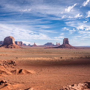 Desert landscape with large rock formations under a blue sky with clouds