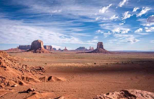 Desert landscape with large rock formations under a blue sky with clouds